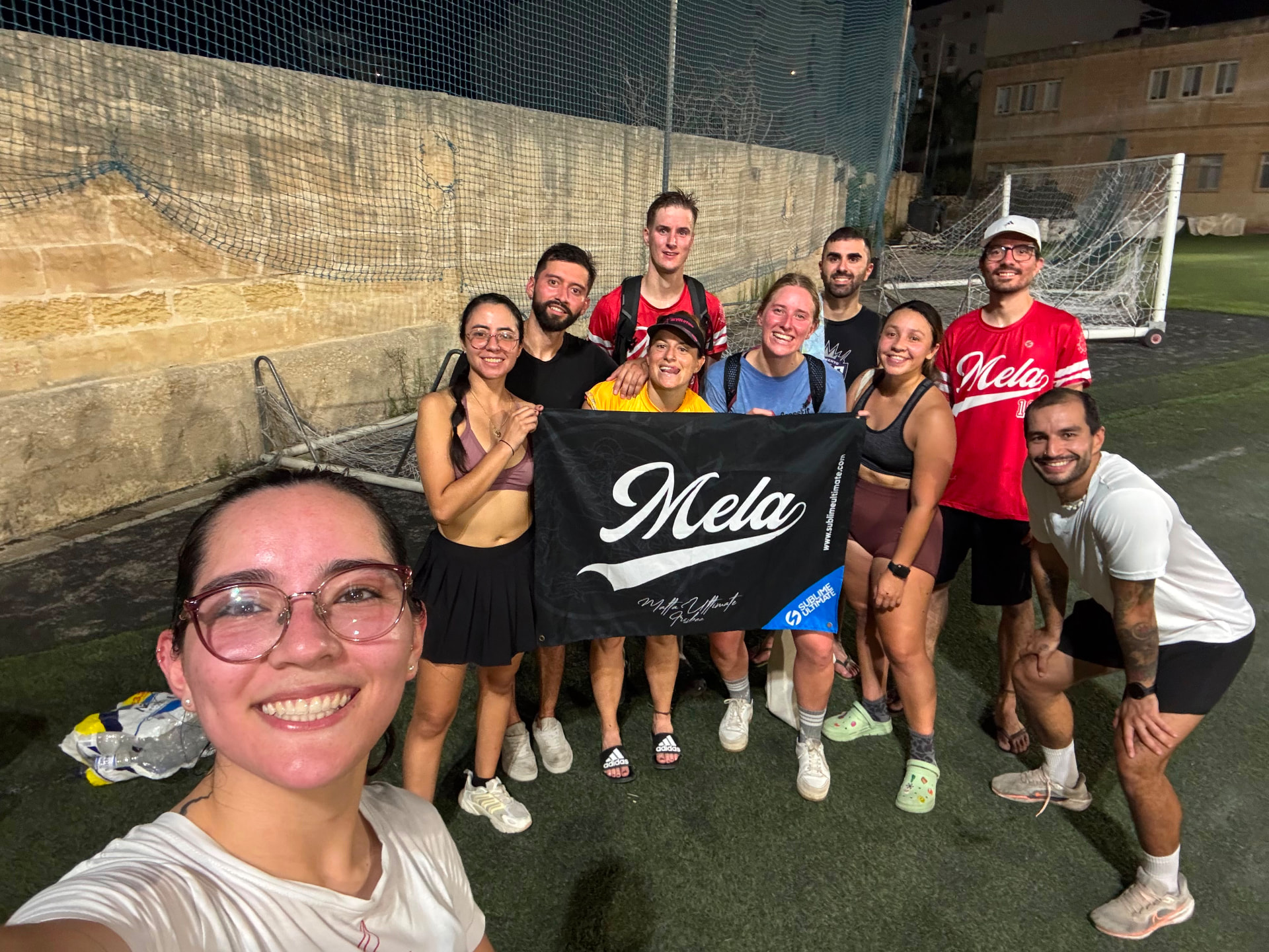 Players holding the Mela Ultimate banner after an evening training session